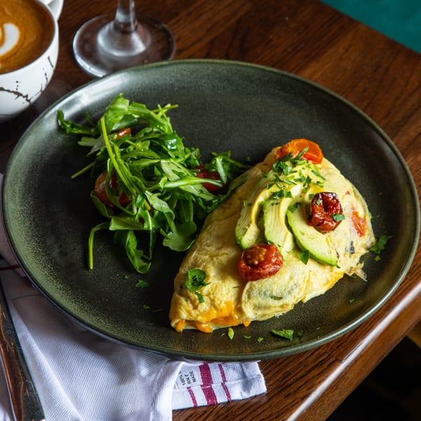 Lyons Corner breakfast omelet with avocado, sun-dried tomatoes, and a side of arugula salad.