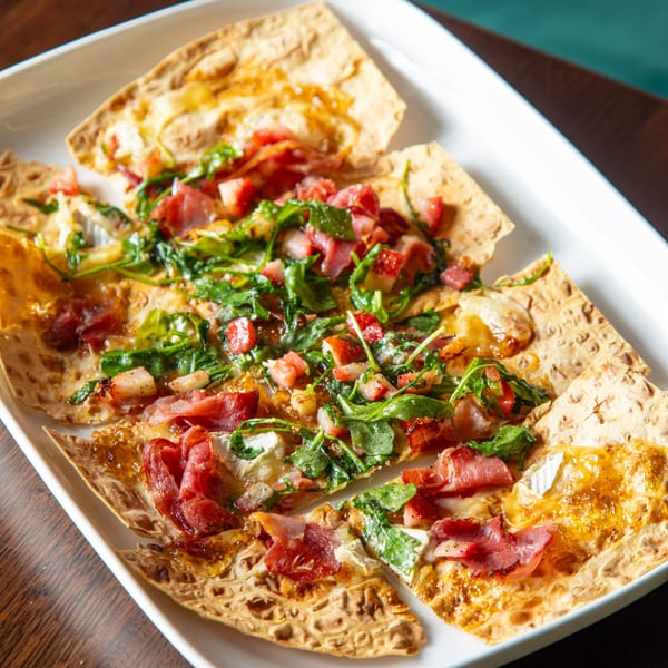 Lyons Corner breakfast flatbread with prosciutto, brie, strawberries, arugula, and honey drizzle.