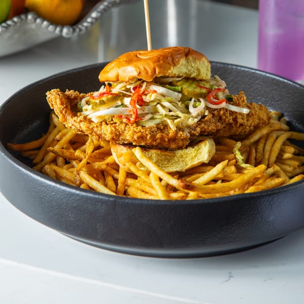 Lyons Corner's fried chicken sandwich with coleslaw, pickles, and red peppers, served with fries.
